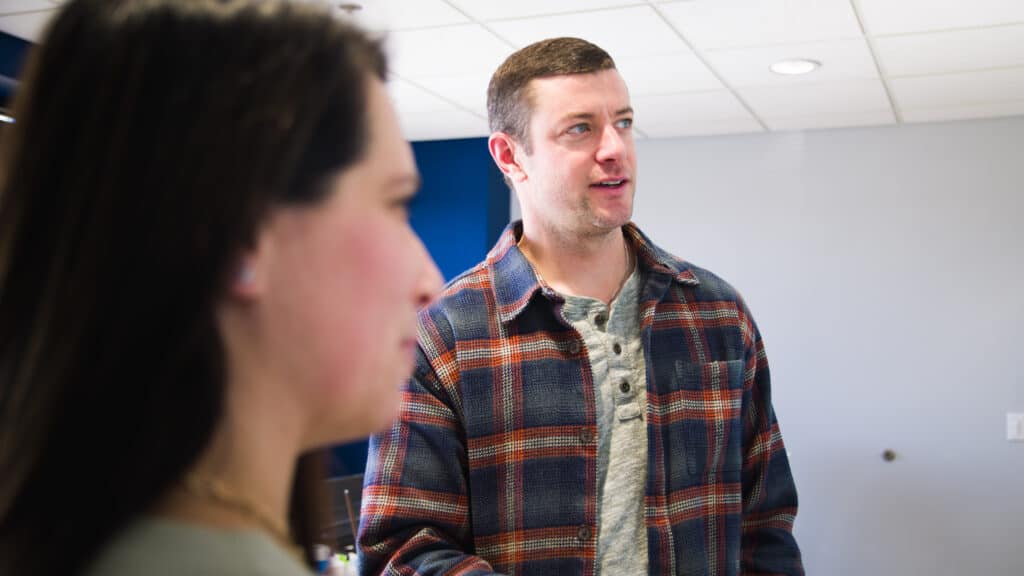 Two Consultants smiling and discussing a project on a whiteboard