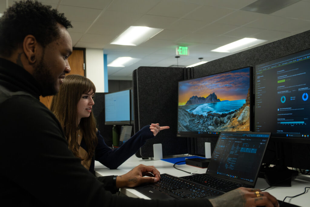 Two people pointing to and talking about a computer error.