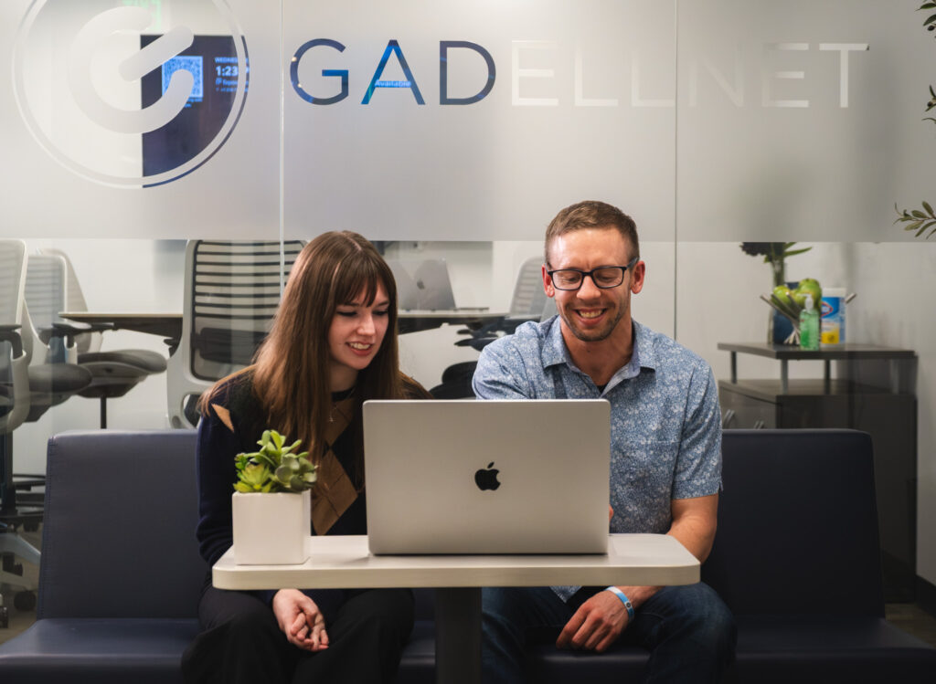 A woman and a man work together on a mac computer.