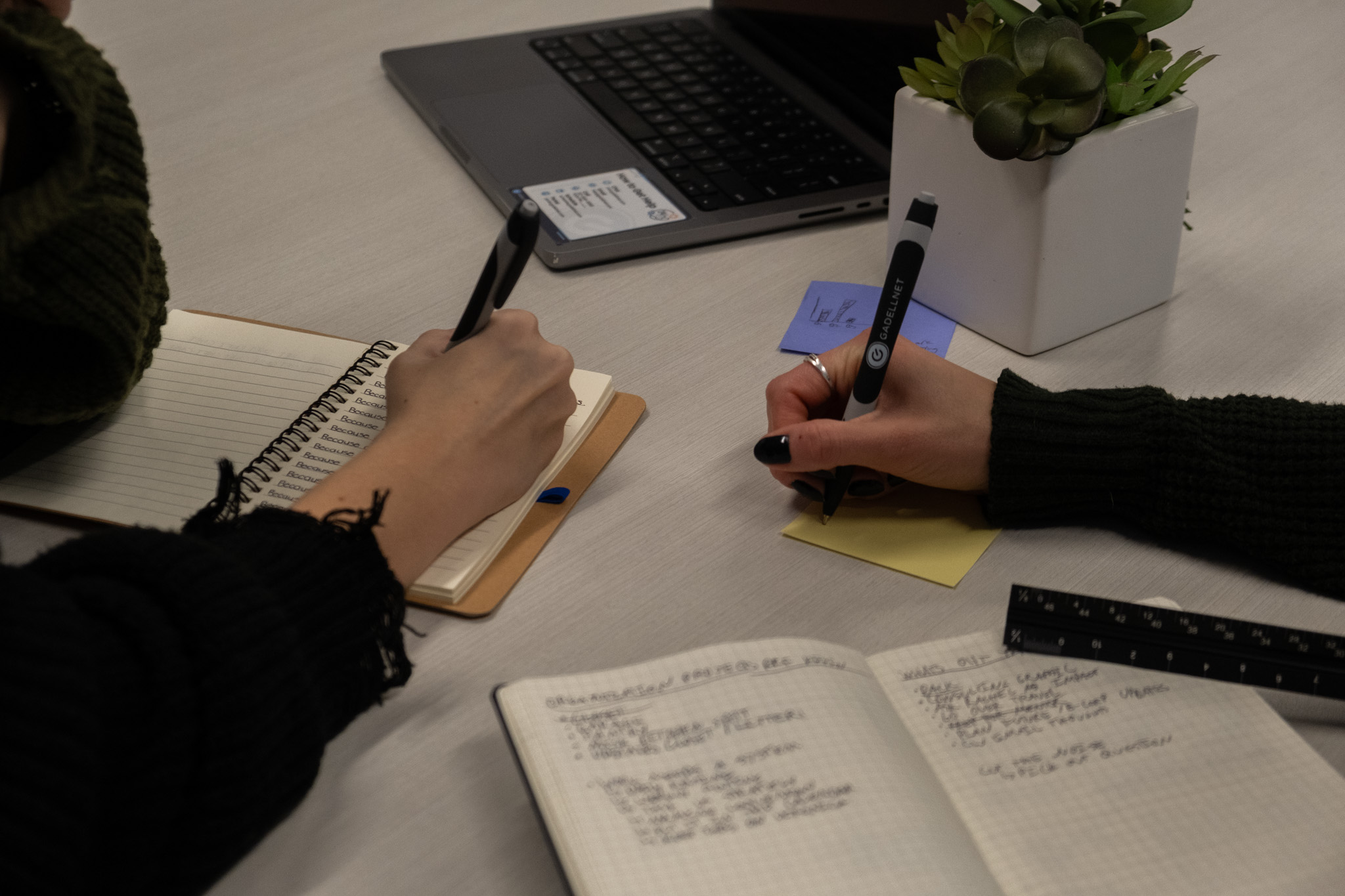 Two hands taking down notes on paper.