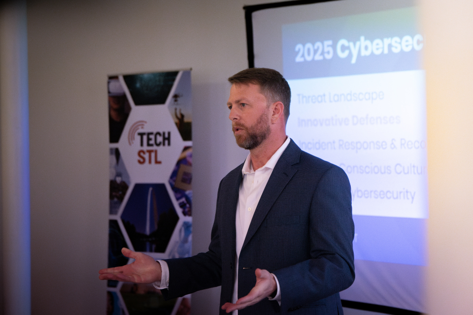 A man with hands gesturing in front of a screen.